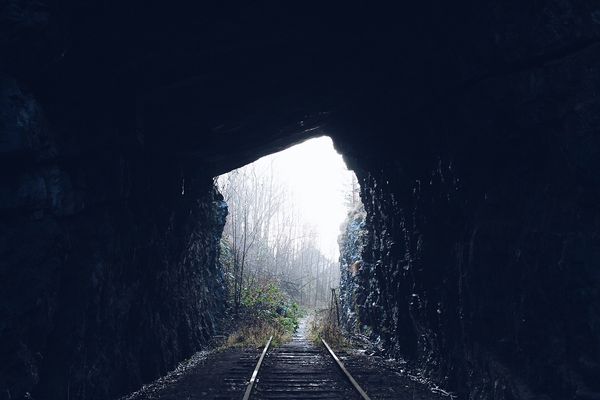 train tracks through tunnel with light at the end