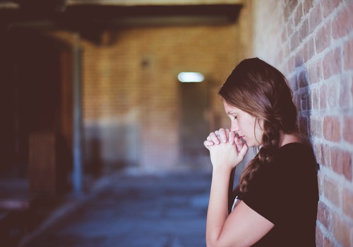 brown haired woman praying in a hallway